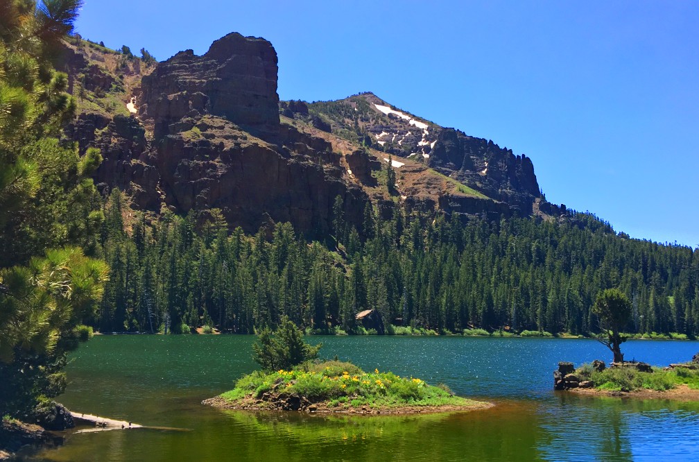 Round Lake is surround by cliffs on one side with a thick pine tree forest along the shore.