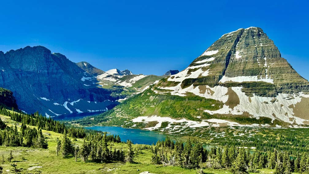 Hidden Lake sits below mountains in the background and forest in the foreground at Glacier National Park.
